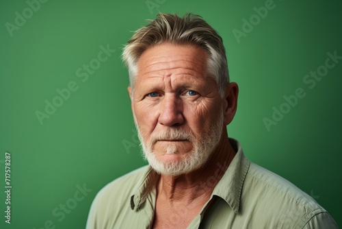 Portrait of a senior man with grey hair and beard on a green background © Iigo