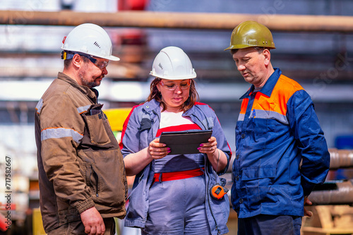A professional team of male and female engineers are discussing a new project using a tablet.Workers are talking about plans. They work at a machine-building and chemical plant.Inspection check.