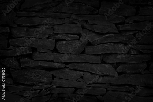 Old dark black stone brick wall texture with vintage style for background and design art work.