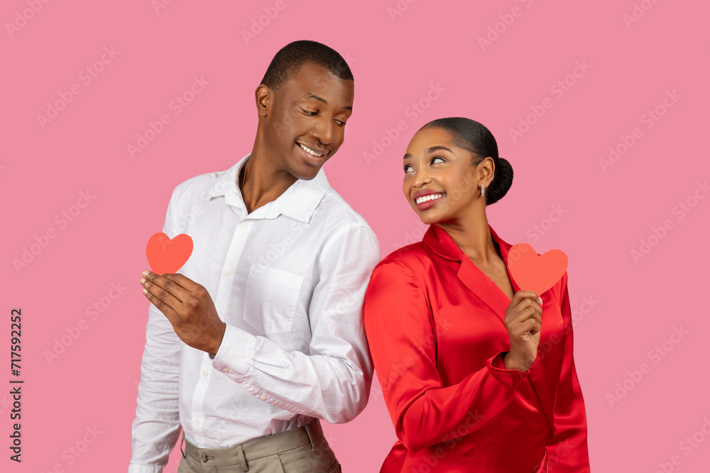 Black couple holding red hearts, man in white, woman in red, playful affection Black couple holding red hearts, man in white, woman in red, playful affection
