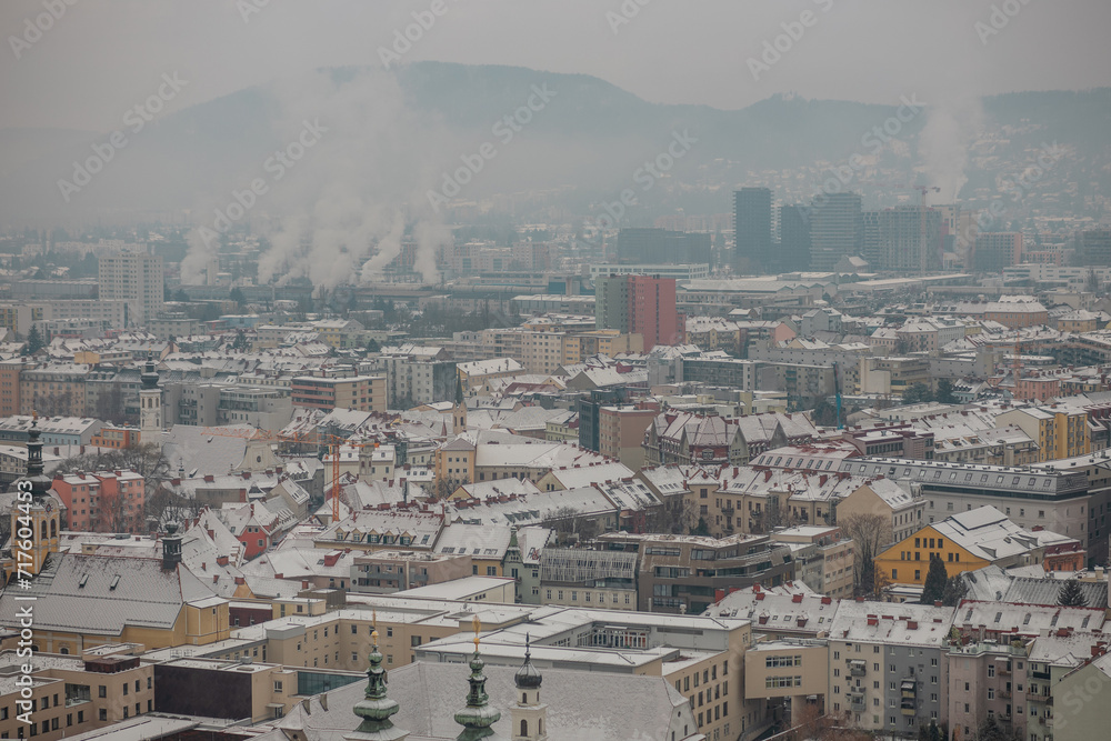 White winter panorama of city of Graz, Austria from famous schlossberg hill. Cold cloudy day, mist rising up.