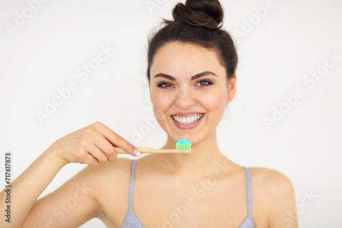 Attractive smiling woman holding toothbrush isolated on white