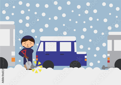 立ち往生した車のマフラー付近の除雪作業を行っている人のイメージ素材