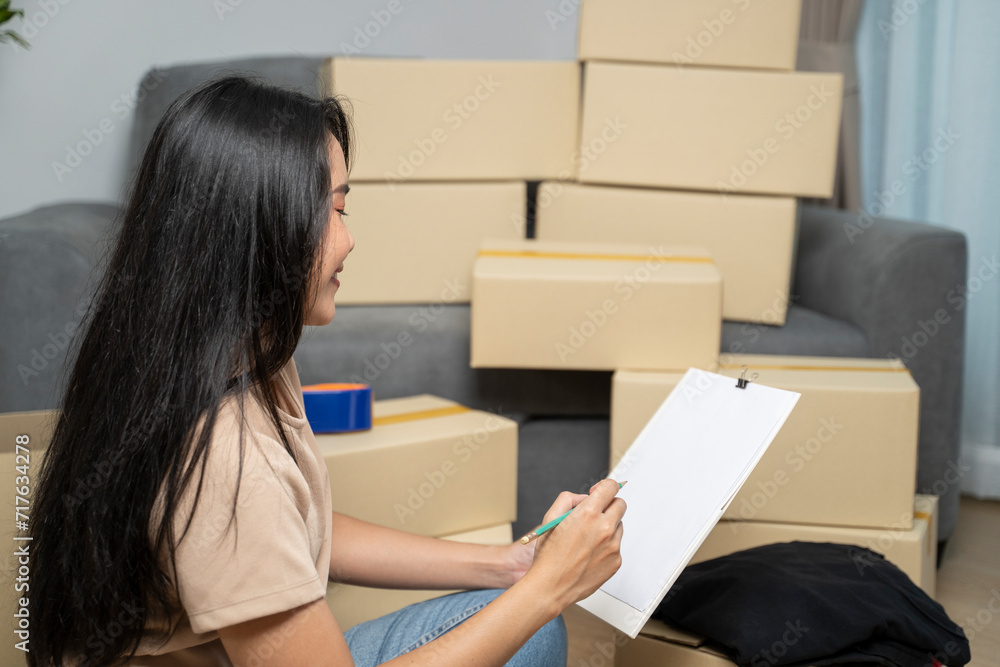 Asian woman doing checklist while packing for new home. Asian woman doing checklist while packing for new home.