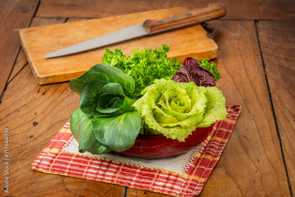 Four salads in a cup on an antique wooden table: green grumolo chicory, radicchio from Chioggia, radicchio from Castelfranco and curly salad. Four salads in a cup on an antique wooden table: green grumolo chicory, radicchio from Chioggia, radicchio from Castelfranco and curly salad.
