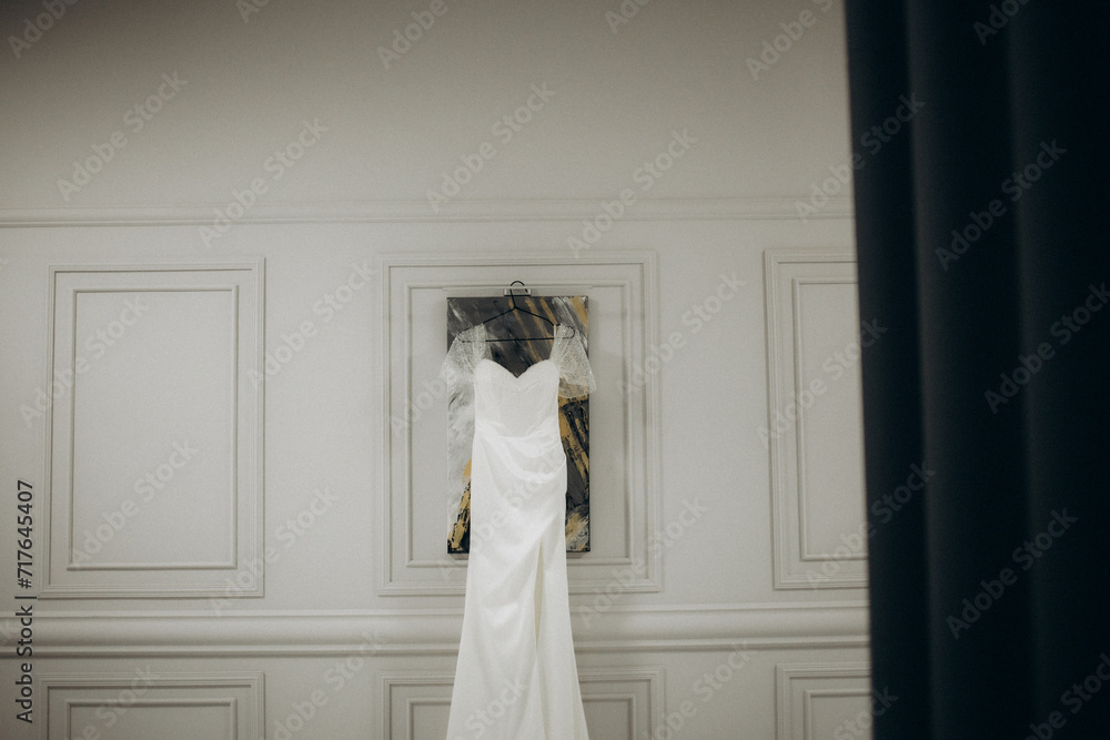 Elegant wedding dress hanging on rack indoors Elegant wedding dress hanging on rack indoors