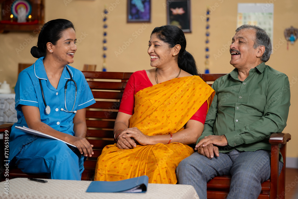 Obraz premium Indian nurse inspiring or giving confidence to senior couples during routine home health checkup - concept of medical consultation, healthcare examination or support