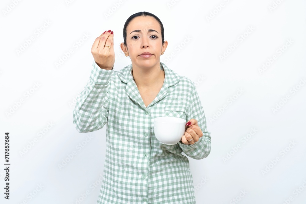 Beautiful young woman wearing green plaid pyjama angry gesturing typical italian gesture with hand, looking to camera Beautiful young woman wearing green plaid pyjama angry gesturing typical italian gesture with hand, looking to camera