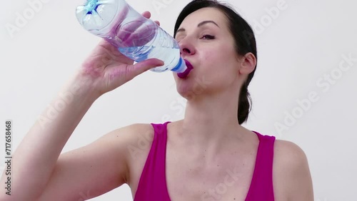 Young woman is exercising on a treadmill and drinking water to hydrate her body, Video Clip 4K