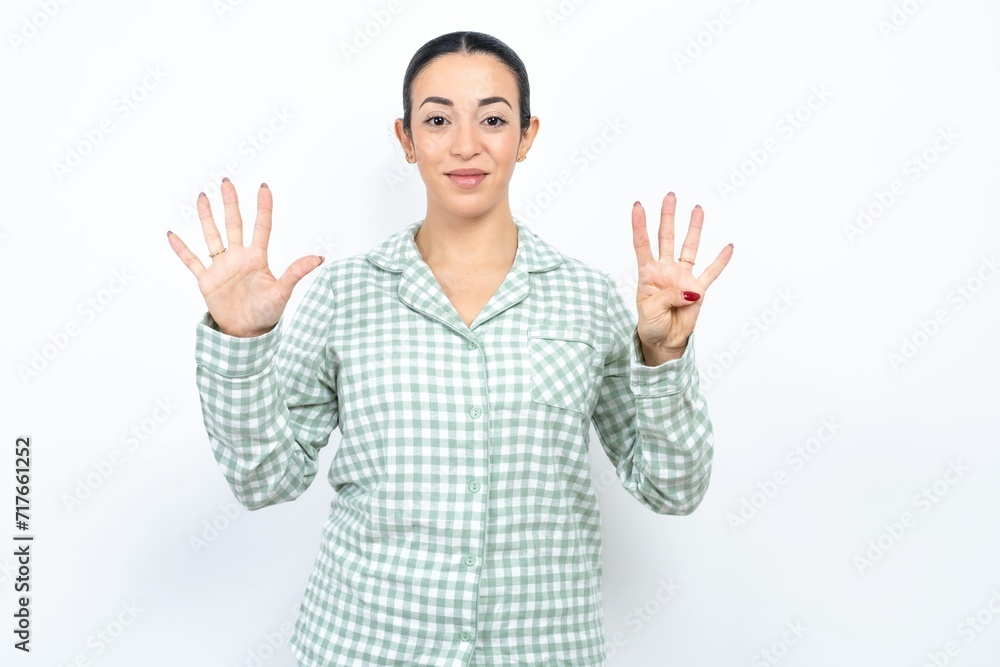 Beautiful young woman wearing green plaid pyjama showing and pointing up with fingers number nine while smiling confident and happy. Beautiful young woman wearing green plaid pyjama showing and pointing up with fingers number nine while smiling confident and happy.
