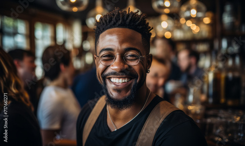 Confident African American Bartender Smiling at a High-End Bar with Sophisticated Ambiance and Colleagues in Background