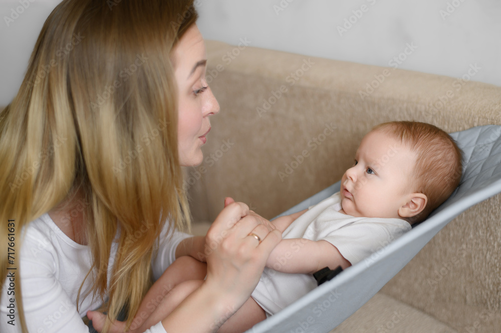 A serious baby is lying in a baby lounger,looking attentively at his mother,the mother is talking to the baby.Family day A serious baby is lying in a baby lounger,looking attentively at his mother,the mother is talking to the baby.Family day