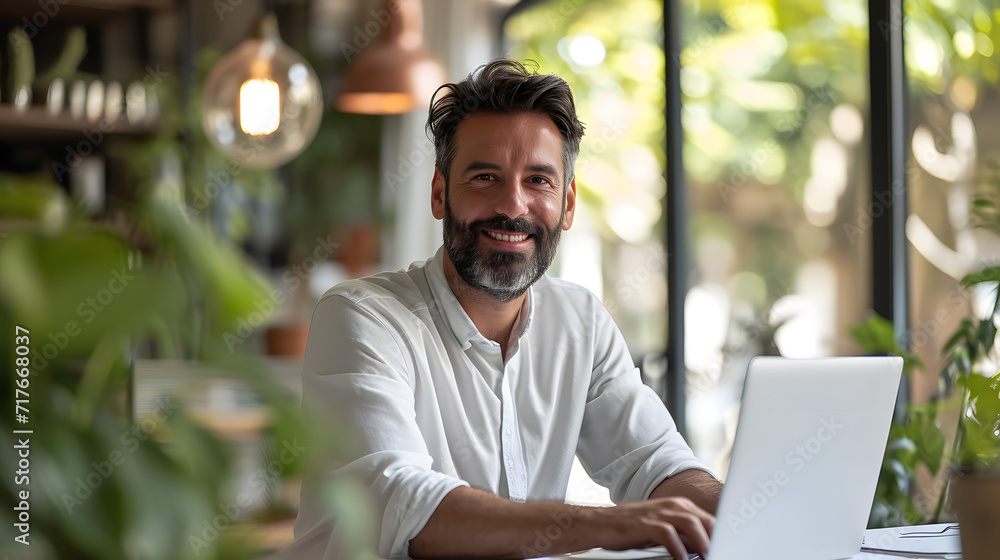 Cheerful male businessman entrepreneur professional working on laptop while sitting at office desk Cheerful male businessman entrepreneur professional working on laptop while sitting at office desk