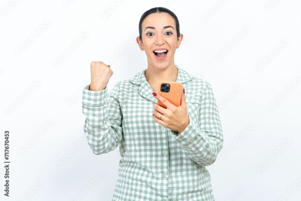 Portrait of Beautiful young woman wearing green plaid pyjama holding in hands cell celebrating Portrait of Beautiful young woman wearing green plaid pyjama holding in hands cell celebrating