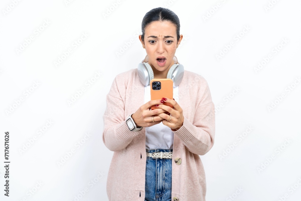 Surprised Young beautiful woman using smartphone reading social media news, or important e-mail Surprised Young beautiful woman using smartphone reading social media news, or important e-mail