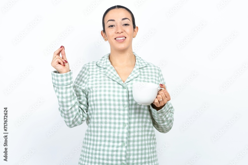 Beautiful young woman wearing green plaid pyjama pointing up with hand showing up seven fingers gesture in Chinese sign language QÄ«.
