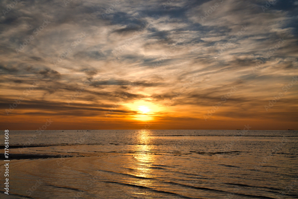 Obraz premium Sunset, illuminated sea. Sandy beach in the foreground. Light waves. Baltic Sea
