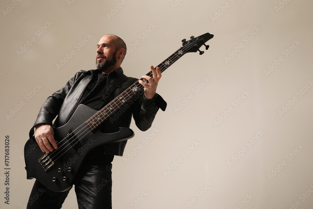 Obraz premium Rock musician. A man with black electric guitar poses at the studio.Mock-up.