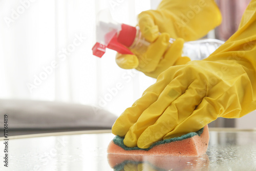 Wallpaper Mural Woman in rubber gloves cleans a coffee table with a spray. Spraying and wiping glass table.	 Torontodigital.ca