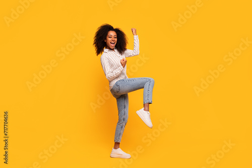 Joyful african american woman dancing on yellow background photo