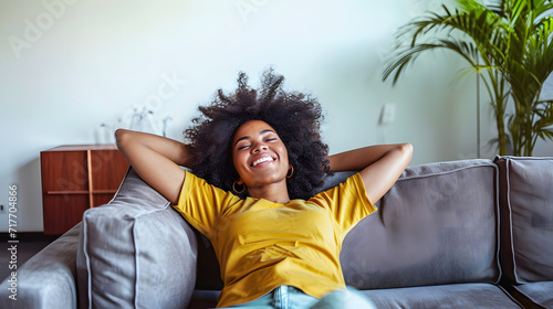 Happy afro american woman relaxing on the sofa at home - Smiling girl enjoying day off lying on the couch - Healthy life style, good vibes people and new home concept photo