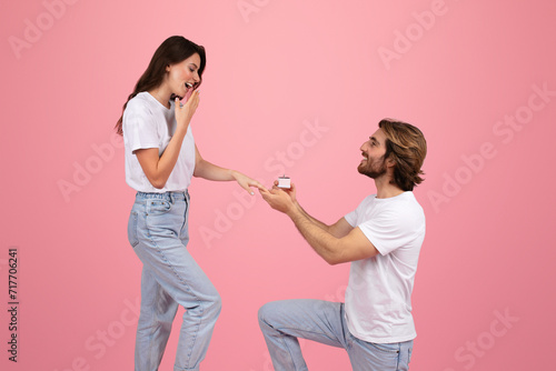 Happy young caucasian man on knee give ring box to surprised woman