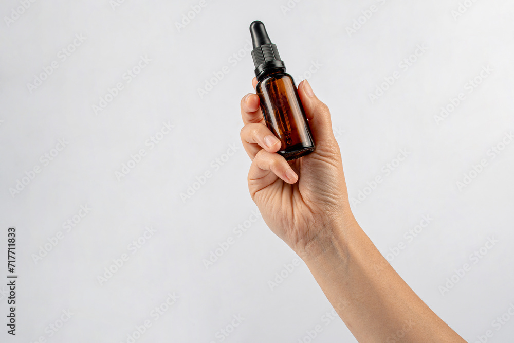 Cosmetic bottles made of dark amber glass in hand on white background Cosmetic bottles made of dark amber glass in hand on white background
