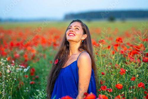 portrait of elegant young woman in poppy field in evening sunlight