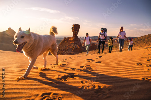 Big family father, mother and little daughters walks with white dog in Gobi desert photo