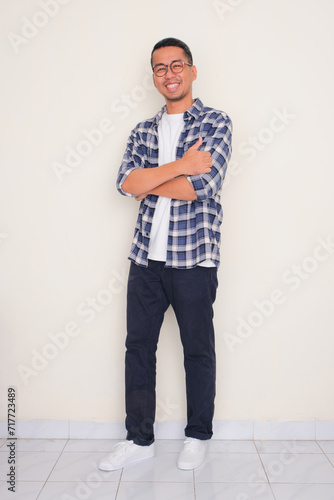 Full body portrait of a man smiling happy ath the camera while giving thumb up photo