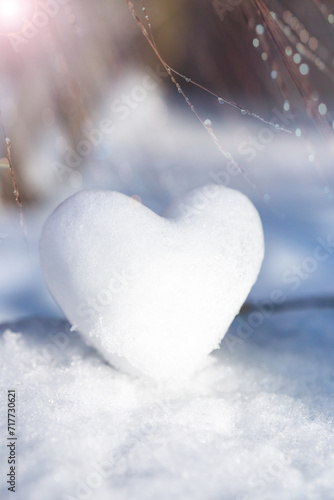 A snowy, tender heart against a winter background with beautiful bokeh.