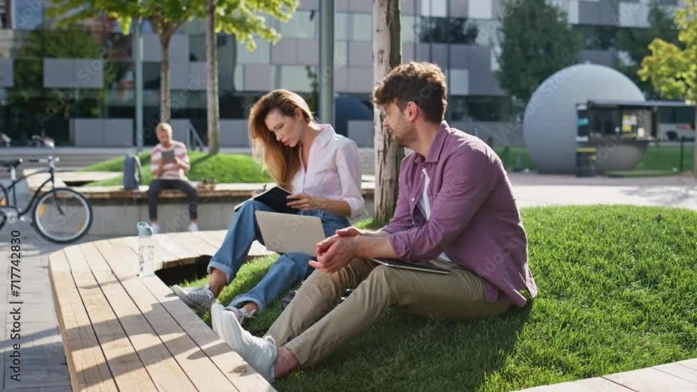 Freelance man finishing work in urban park. Smiling colleagues working remotely Freelance man finishing work in urban park. Smiling colleagues working remotely