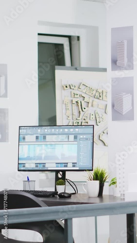 Vertical Video Cad modeling system running on PC at a empty workstation, urbanistic designs and layouts on table. Innovative architectural creative business desktops equipped with manufacturing tools. photo