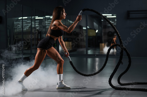 Caucasian woman doing exercise with ropes. 