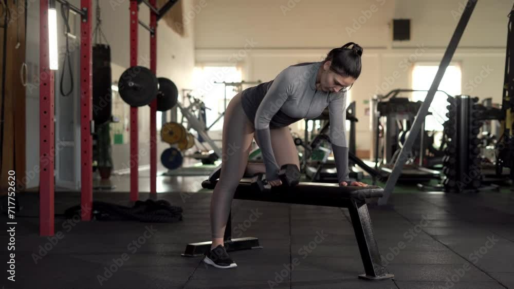 Strength, sport and fitness concept. Woman doing exercise with dumbbell standing on sports bench in the gym. Strength, sport and fitness concept. Woman doing exercise with dumbbell standing on sports bench in the gym.