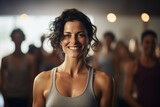 a woman smiles in front of many people in a yoga class