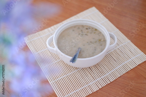 Mung Bean Porridge or Bubur Kacang Hijau, Indonesian dessert porridge of mung beans with coconut milk, pandan leaf and ginger. Served in bowl.