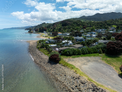 Aerial: Flowering Pohutukawa trees and beach coastline in Waiomu, near Thames, Coromandel Peninsula, New Zealand. photo