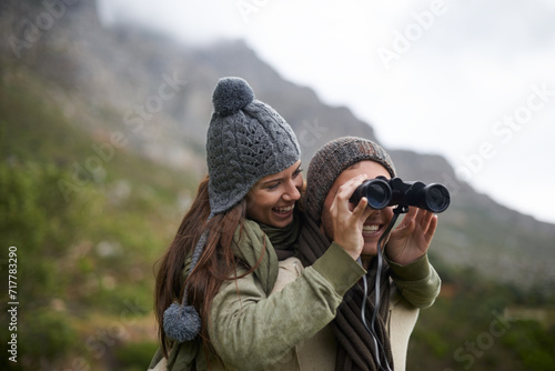 Happy couple, binoculars in nature and mountains for travel journey, adventure and hiking or explore together. Man and woman trekking for outdoor search, vision or birdwatching lens of winter tourism