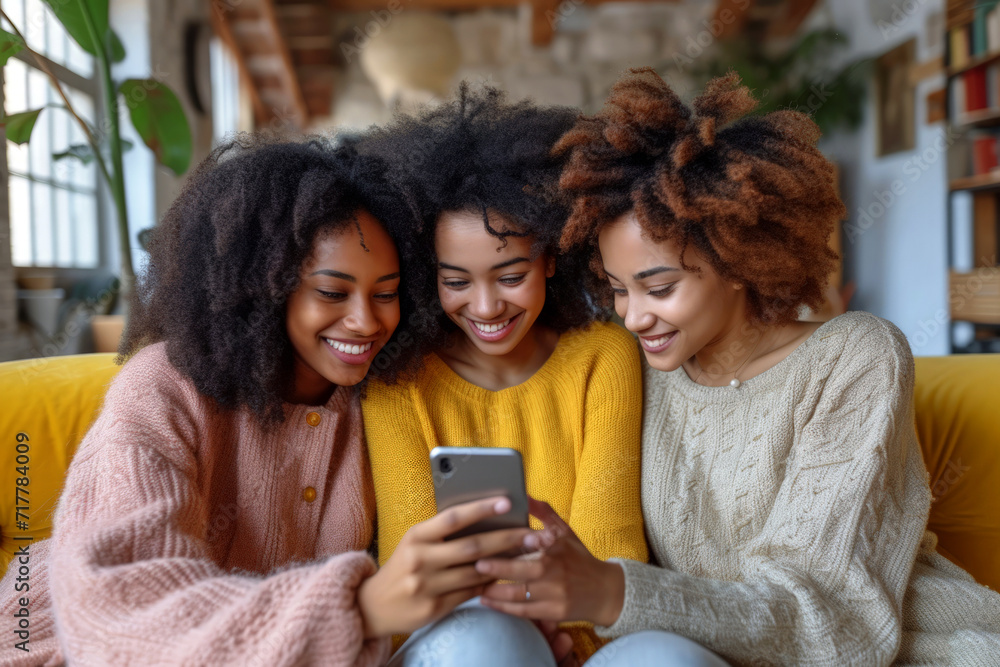 Three afro girls sharing a delightful moment on a yellow couch looking at a smartphone together. Three afro girls sharing a delightful moment on a yellow couch looking at a smartphone together.