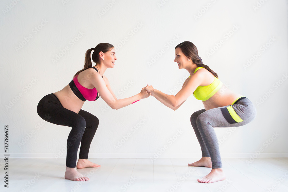 Two young pregnant women doing fitness exercises