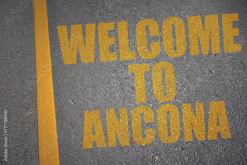 asphalt road with text welcome to Ancona near yellow line.