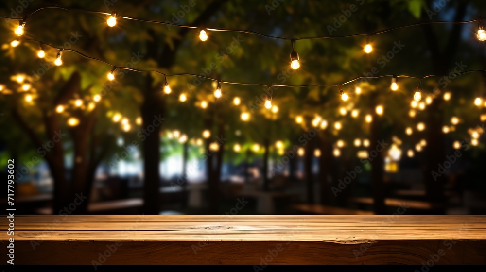 Empty wood table top with outdoor string lights hanging on tree in garden at night - fairy lights