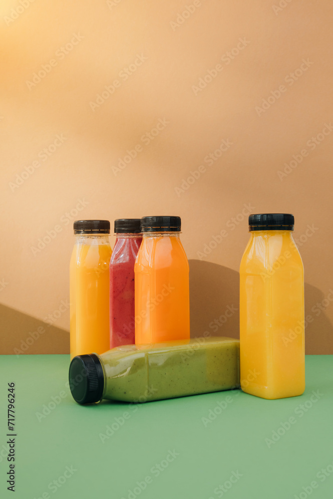 Fruit and vegetable smoothies in transparent plastic bottles. Red, green, orange smoothies on a brown-green background. The concept of healthy eating. Front view Fruit and vegetable smoothies in transparent plastic bottles. Red, green, orange smoothies on a brown-green background. The concept of healthy eating. Front view