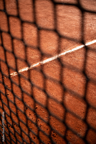 clay court with tennis net blurred in foreground, tennis event photo