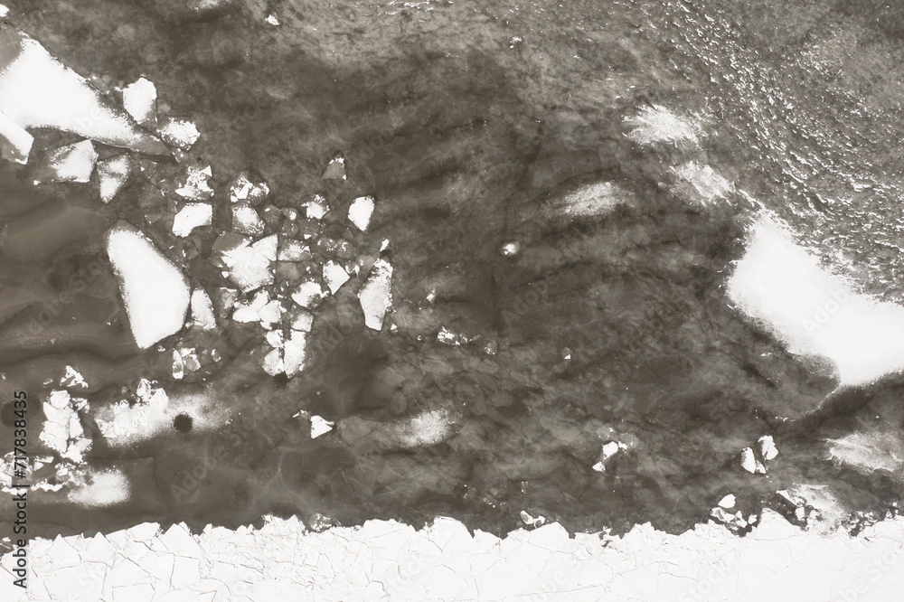The texture of a frozen lake and pieces of floating ice in the water. Winter landscape from a drone.