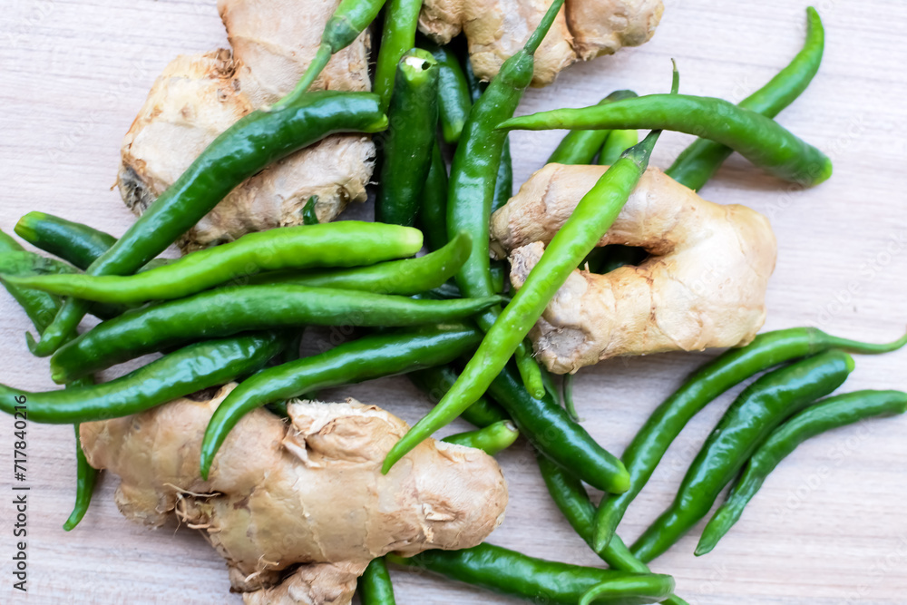 Fresh Ginger and green chili pepper on plain wooden table, green essential vegetables for all essential foods, view of unpeeled vegetables with plain background Fresh Ginger and green chili pepper on plain wooden table, green essential vegetables for all essential foods, view of unpeeled vegetables with plain background