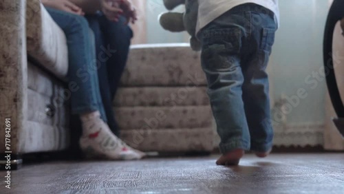 A small child takes the first steps on the floor, legs photo
