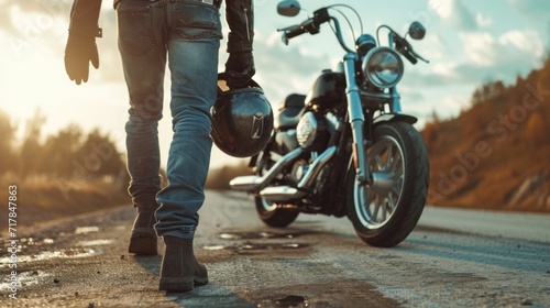 Biker walks to motorcycle holding helmet in hand photo
