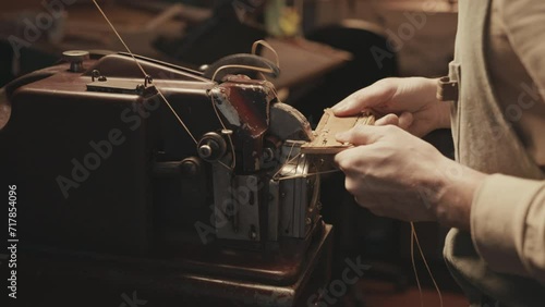 Hand of shoemaker using old-fashioned sewing machine for leatherwork in workshop photo
